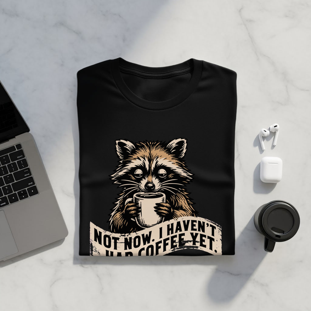 Black t-shirt with raccoon holding coffee and text: NOT NOW. I HAVEN'T HAD COFFEE YET.