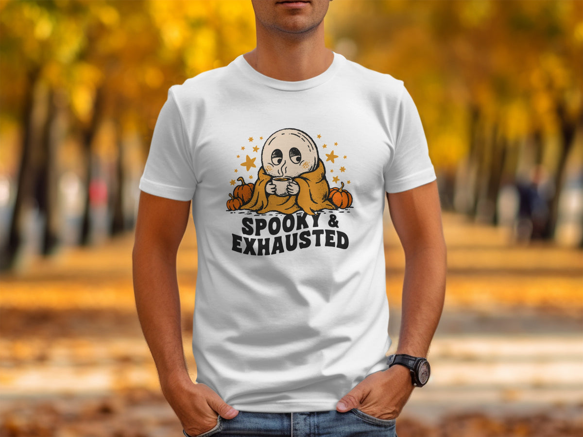 White t-shirt with a cartoon ghost holding a coffee cup, pumpkins, and stars, text reads "SPOOKY & EXHAUSTED".