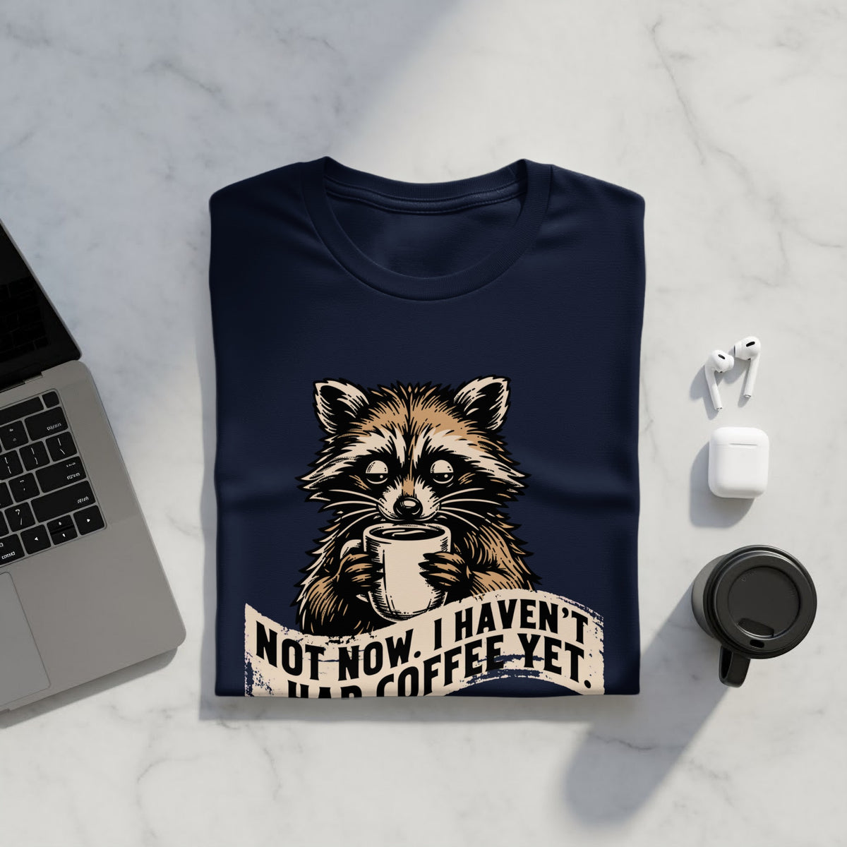 Navy t-shirt with raccoon graphic saying "Not Now, I Haven't Had Coffee Yet."