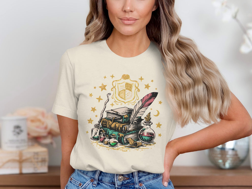 T-shirt with stack of books, feather quill, potion bottles, and magical crest.