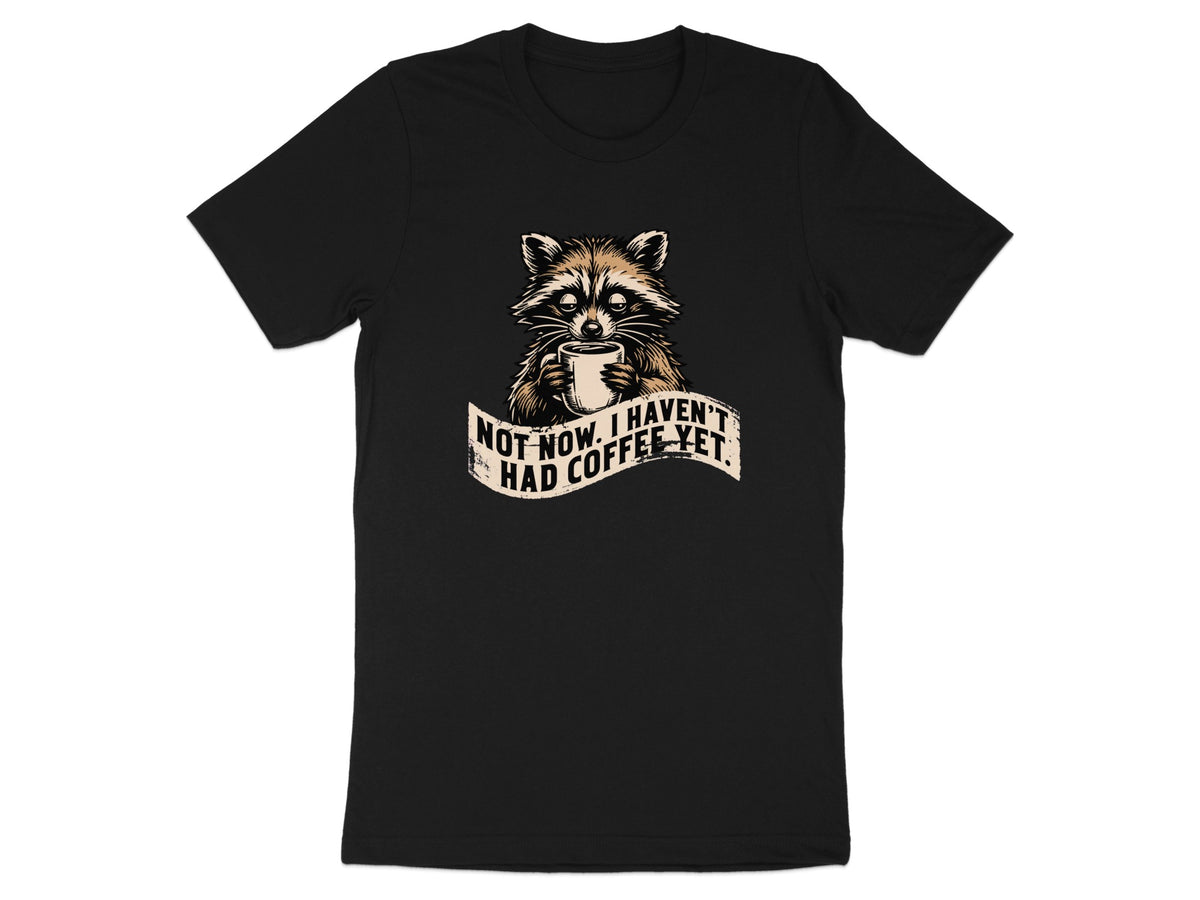 Black t-shirt featuring a raccoon holding a coffee cup with text "Not now. I haven't had coffee yet."