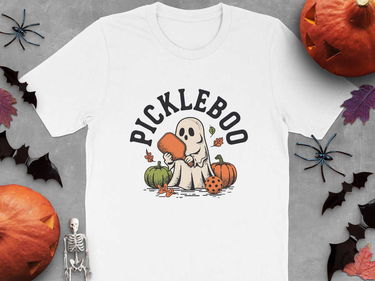 White t-shirt featuring a ghost playing pickleball with pumpkins and autumn leaves.