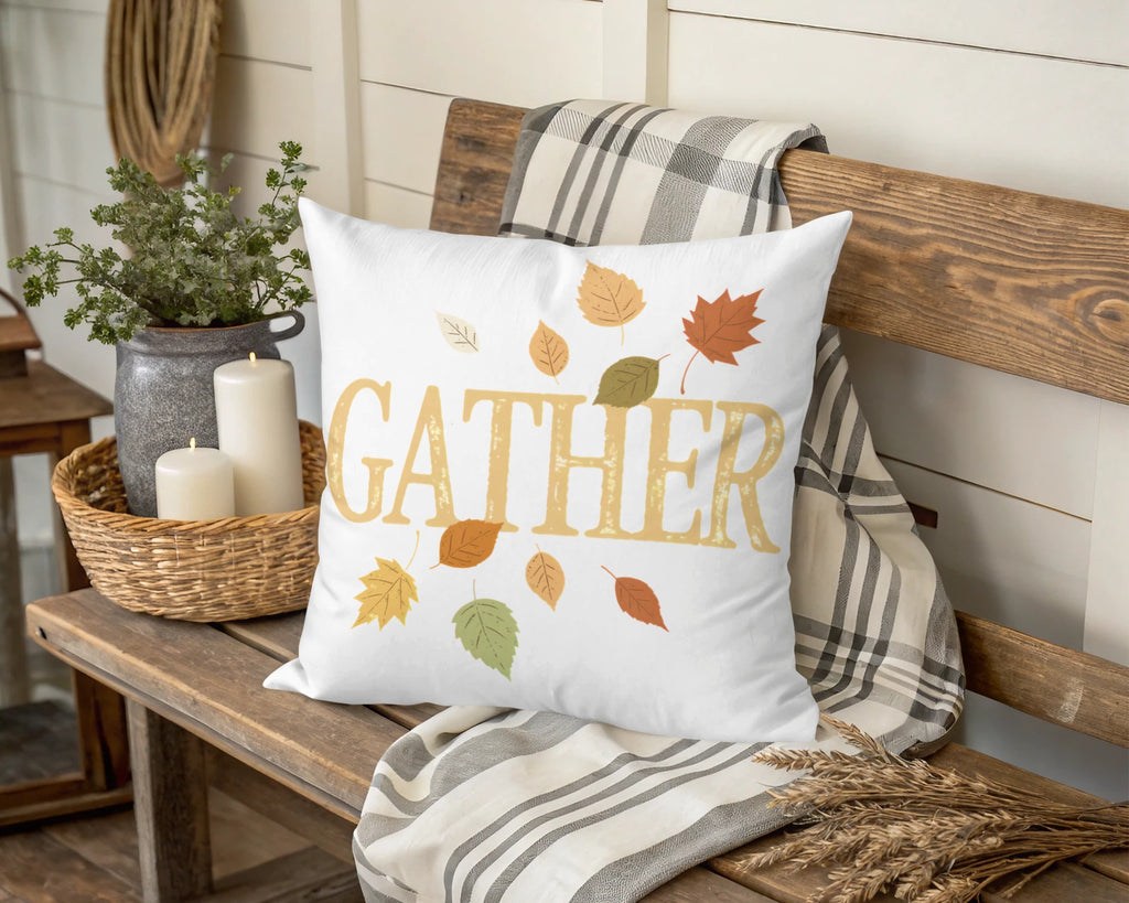 White pillow with "Gather" and falling autumn leaves design.