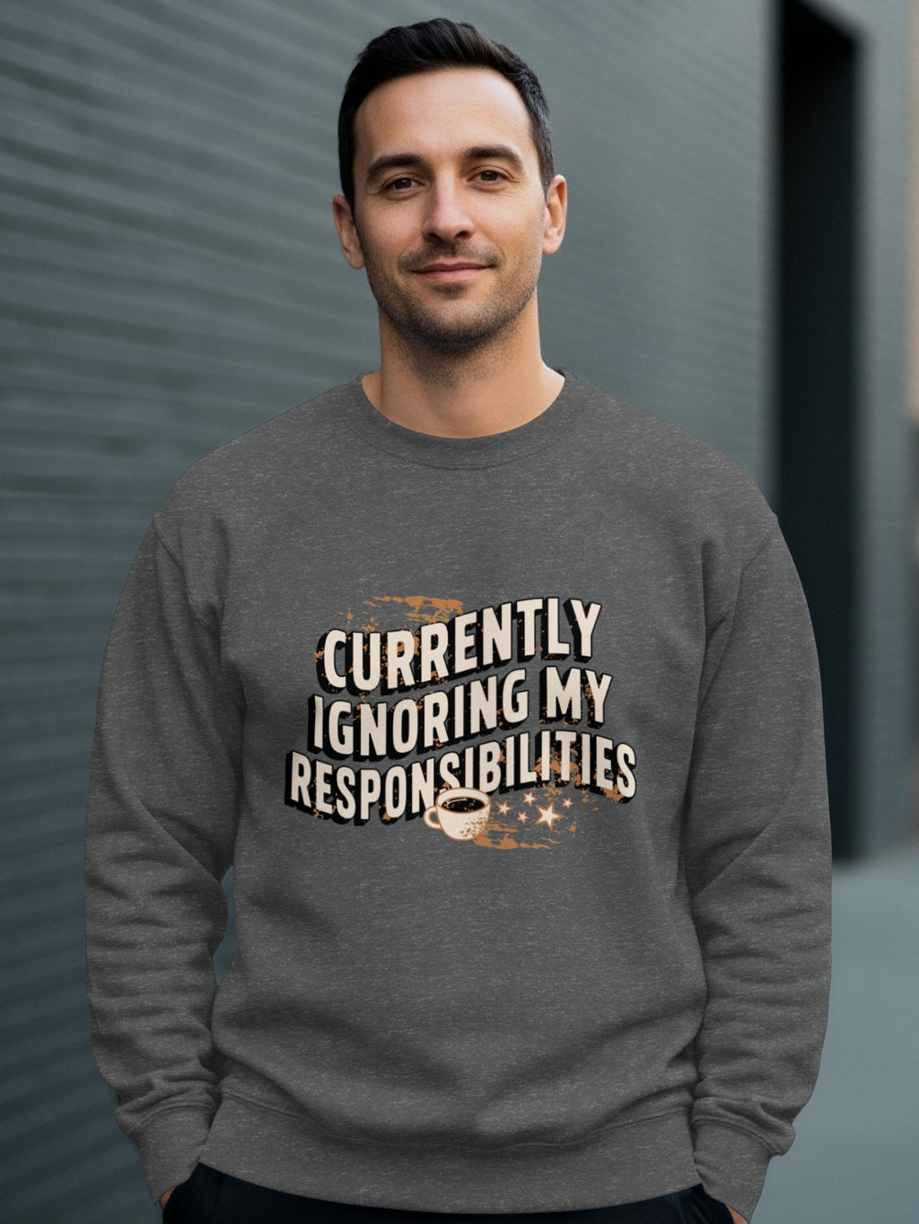 Man in grey sweatshirt with "Currently Ignoring My Responsibilities" text and coffee cup.