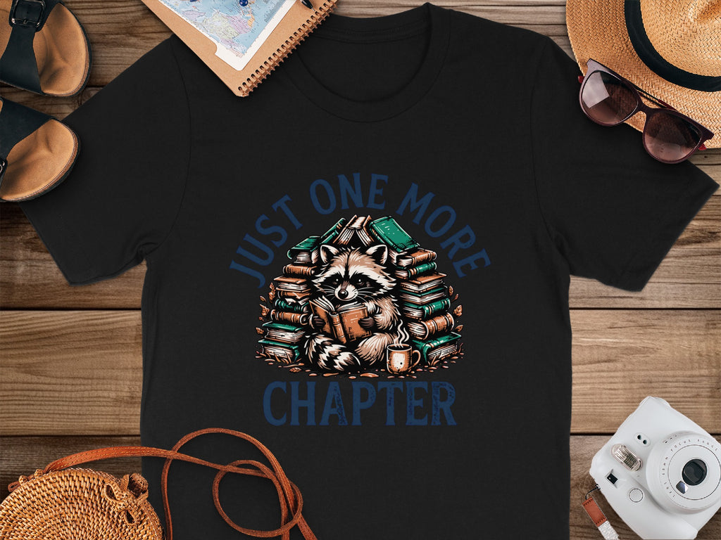 Black t-shirt with raccoon reading books and text "JUST ONE MORE CHAPTER".