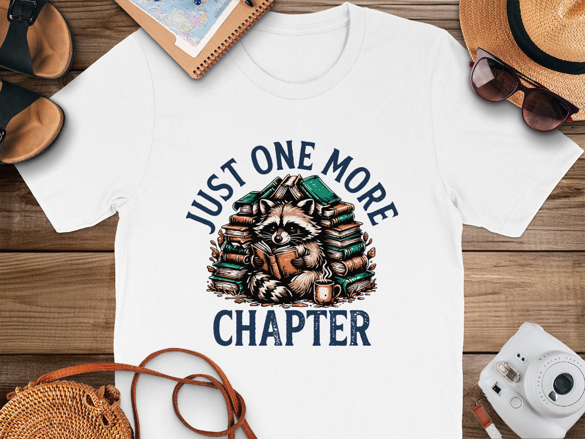 White t-shirt with raccoon reading books text "JUST ONE MORE CHAPTER"