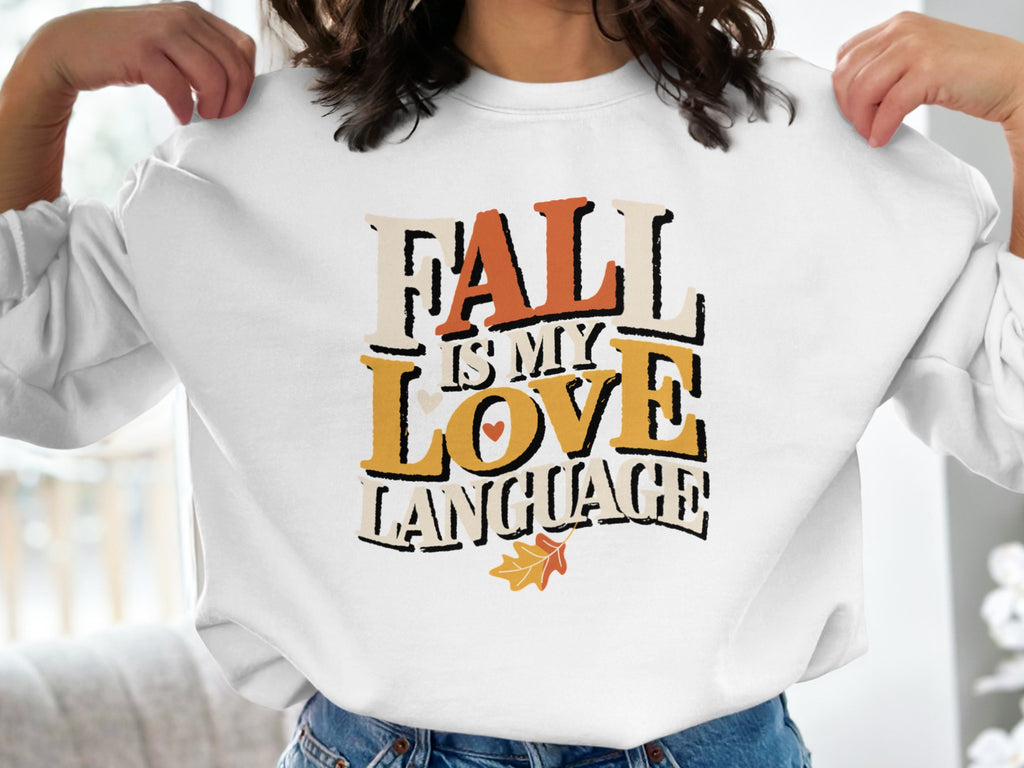 White sweatshirt with text "Fall is my love language" and fall leaf accent.