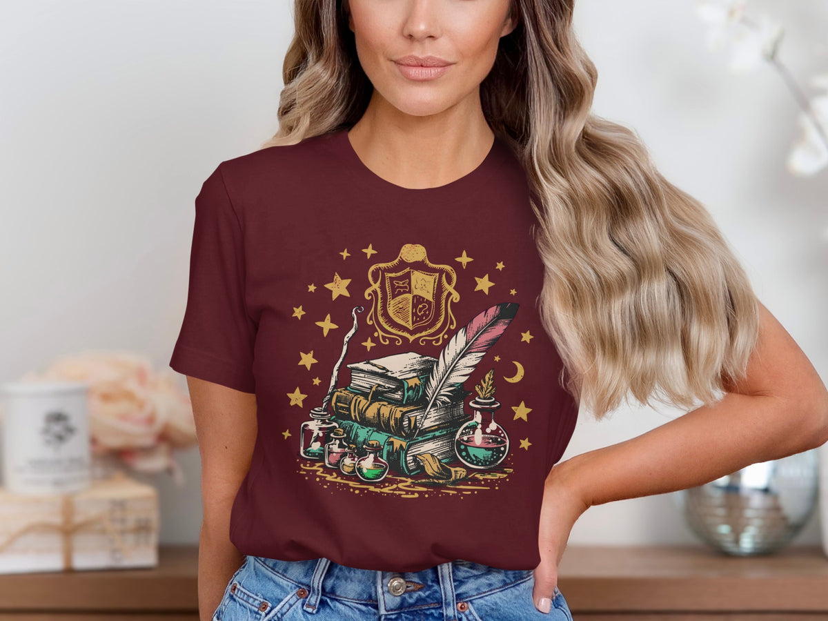 T-shirt graphic with books, potions, quill, and crest surrounded by stars.