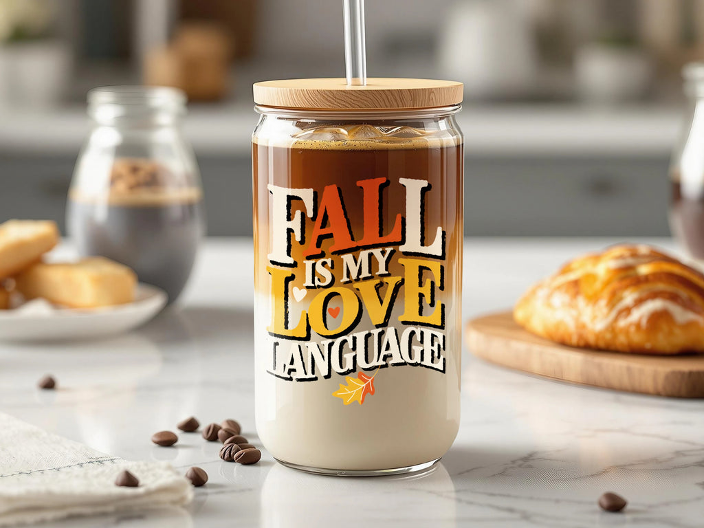 Glass tumbler with lid and straw featuring "Fall is my love language" text and autumn leaf graphics.