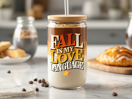 Glass tumbler with lid and straw featuring "Fall is my love language" text and autumn leaf graphics.