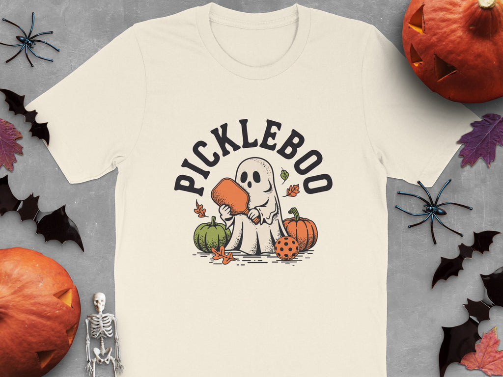 Cream t-shirt with cartoon ghost playing pickleball and "PICKLEBOO" text.