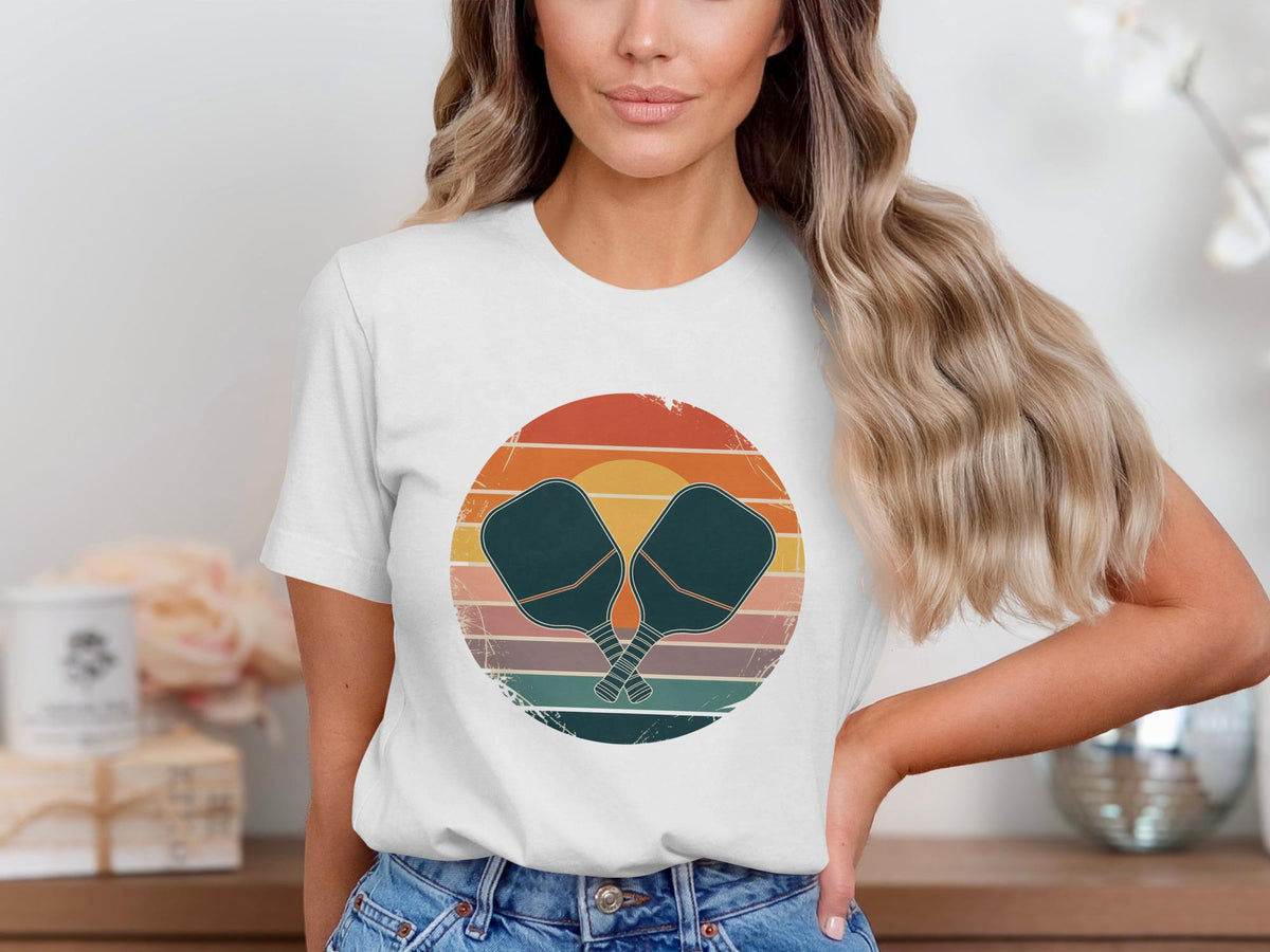 White t-shirt with a distressed circle graphic featuring crossed pickleball paddles and stripes.