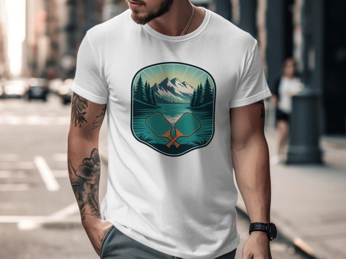 White t-shirt with graphic of crossed pickleball paddles and mountain lake scene.